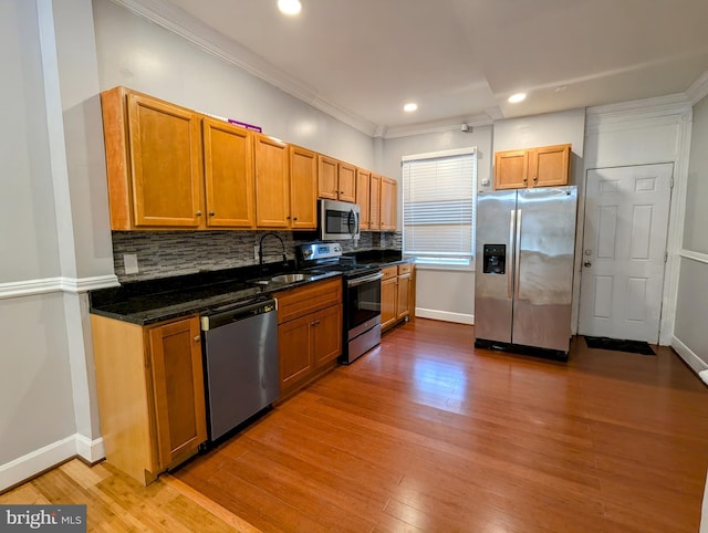 kitchen featuring sink, decorative backsplash, stainless steel appliances, and dark stone counters