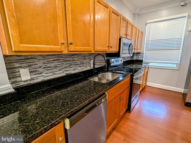 kitchen with sink, crown molding, stainless steel appliances, and dark stone counters