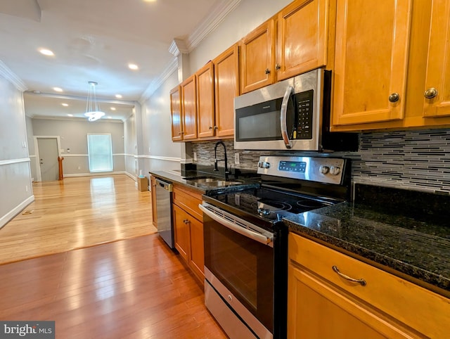 kitchen with sink, dark stone counters, hanging light fixtures, light hardwood / wood-style floors, and stainless steel appliances