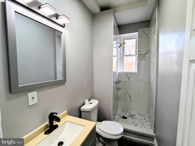 bathroom featuring vanity, a tile shower, and toilet