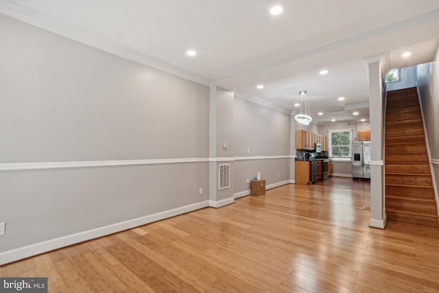 unfurnished living room featuring crown molding and light wood-type flooring