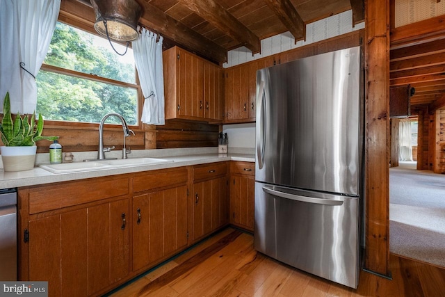 kitchen with wood ceiling, appliances with stainless steel finishes, light wood-type flooring, beam ceiling, and sink