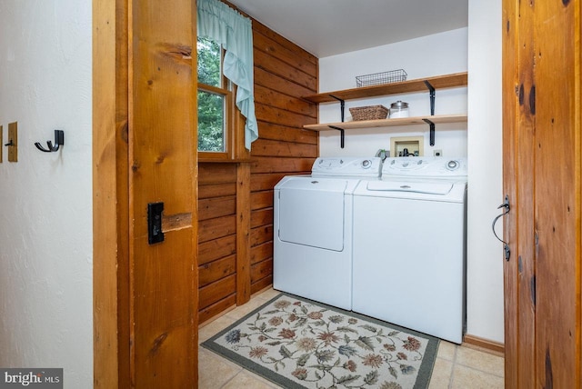 washroom featuring washing machine and dryer, wood walls, and log walls