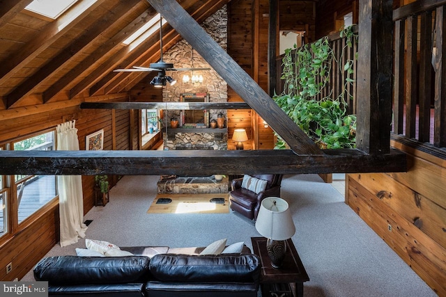 carpeted living room with ceiling fan, lofted ceiling with skylight, wood ceiling, and wooden walls