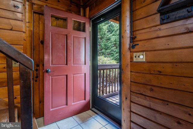 foyer entrance with light tile patterned floors and wooden walls