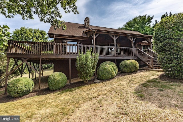 rear view of house featuring a wooden deck and a yard