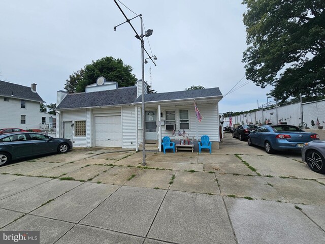 view of front of home with covered porch, a garage, and cooling unit