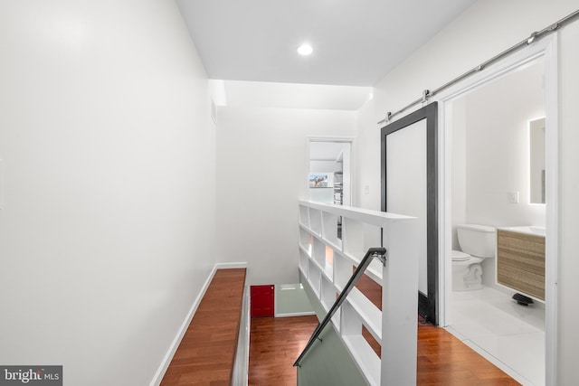 hall featuring a barn door and dark wood-type flooring