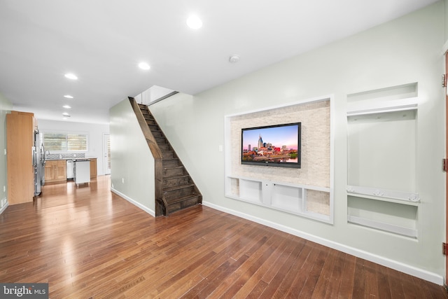 unfurnished living room featuring hardwood / wood-style flooring and built in shelves