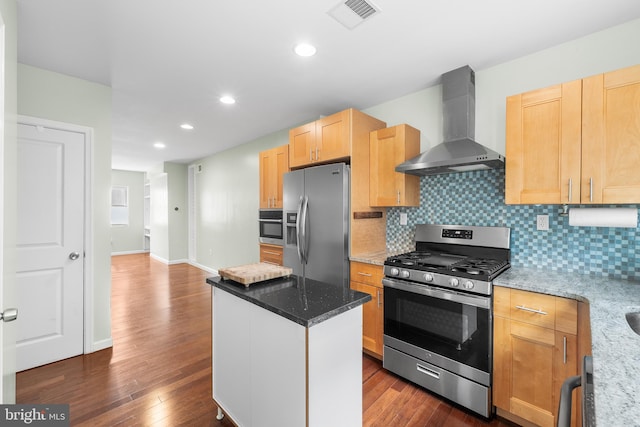 kitchen with wall chimney range hood, decorative backsplash, light stone counters, a kitchen island, and appliances with stainless steel finishes