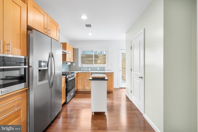 kitchen with decorative backsplash, appliances with stainless steel finishes, dark hardwood / wood-style floors, and light brown cabinets