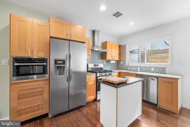 kitchen featuring a kitchen island, appliances with stainless steel finishes, dark wood-type flooring, and wall chimney exhaust hood