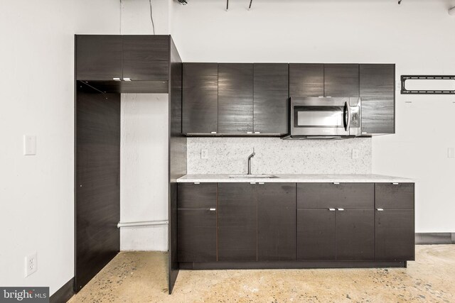 kitchen featuring decorative backsplash, dark brown cabinets, and sink