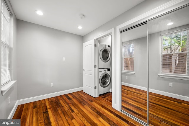 clothes washing area featuring stacked washer / drying machine and dark wood-type flooring