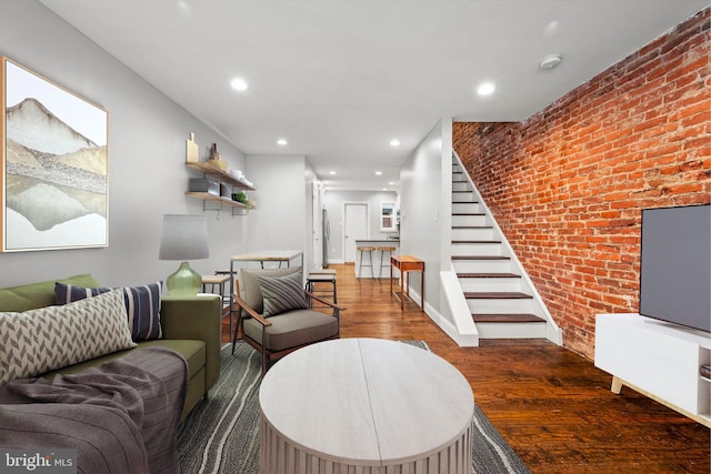 living room featuring brick wall and dark hardwood / wood-style floors