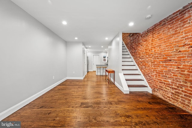 interior space with brick wall and hardwood / wood-style flooring