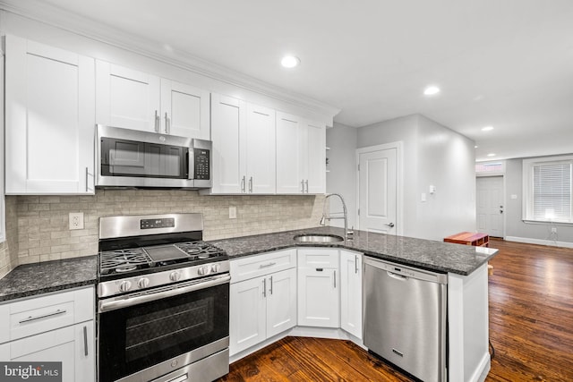 kitchen with sink, white cabinets, appliances with stainless steel finishes, and kitchen peninsula