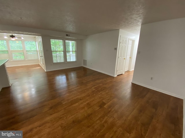 unfurnished living room with ceiling fan, dark hardwood / wood-style flooring, and a textured ceiling