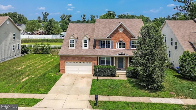 view of front facade with driveway, a front lawn, fence, a garage, and brick siding