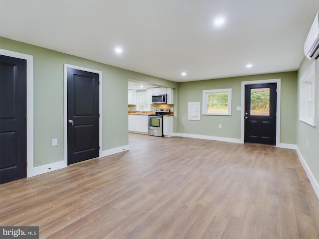 unfurnished living room with an AC wall unit and light wood-type flooring