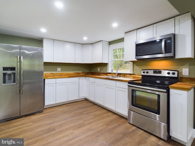 kitchen featuring stainless steel appliances, white cabinets, and wooden counters