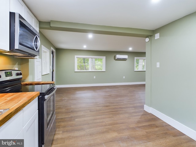 kitchen featuring stainless steel appliances, a wall mounted AC, wooden counters, and white cabinets