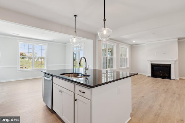 kitchen featuring white cabinetry, an island with sink, decorative light fixtures, stainless steel dishwasher, and sink