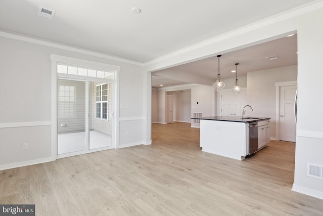 kitchen featuring decorative light fixtures, stainless steel dishwasher, sink, white cabinetry, and light wood-type flooring