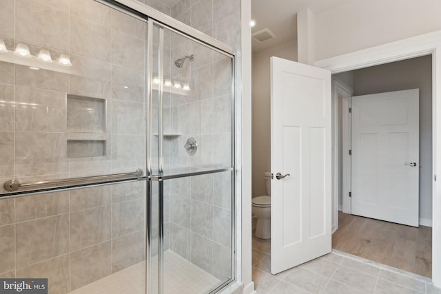 bathroom featuring tile patterned floors, walk in shower, and toilet