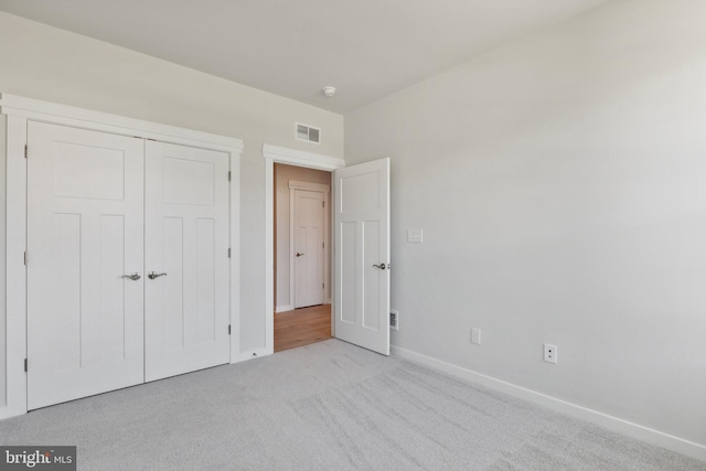 unfurnished bedroom with light carpet and a closet