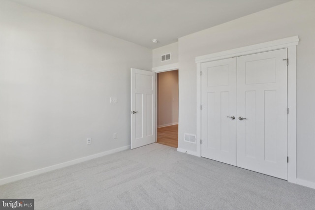 unfurnished bedroom with a closet and light colored carpet