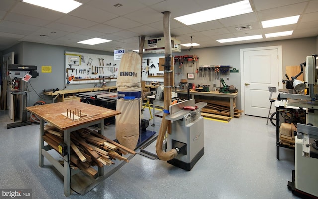 miscellaneous room with a paneled ceiling and a workshop area