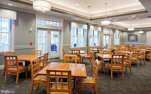 dining space featuring a tray ceiling, ornamental molding, french doors, and dark colored carpet