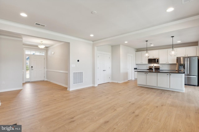 kitchen with pendant lighting, light hardwood / wood-style flooring, a kitchen island with sink, stainless steel appliances, and white cabinets