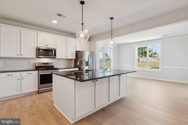 kitchen with decorative light fixtures, white cabinetry, appliances with stainless steel finishes, and a center island with sink