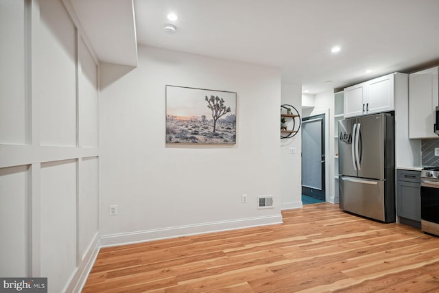 kitchen featuring decorative backsplash, light hardwood / wood-style floors, white cabinetry, and stainless steel appliances