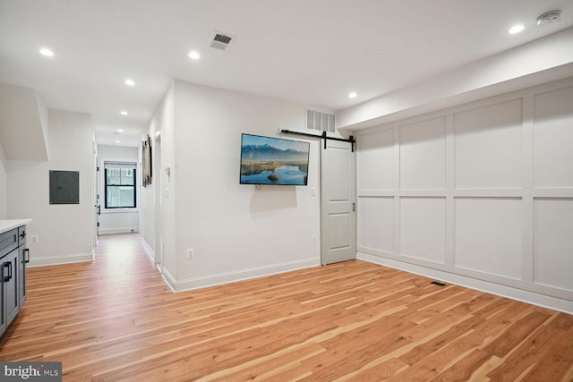 interior space featuring electric panel, a barn door, and light hardwood / wood-style flooring