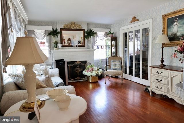 living area featuring dark wood-type flooring, french doors, and a brick fireplace