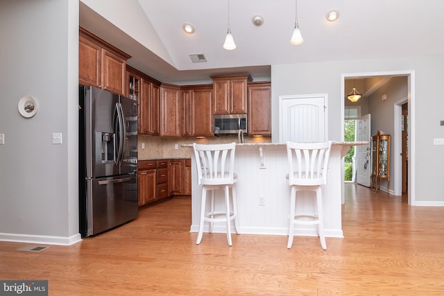 kitchen featuring light wood-type flooring, a breakfast bar area, stainless steel appliances, and a center island