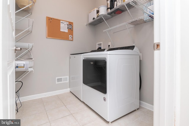 laundry room with washing machine and dryer and light tile patterned floors