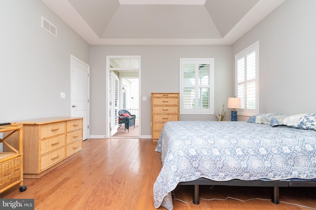 bedroom with wood-type flooring and a tray ceiling