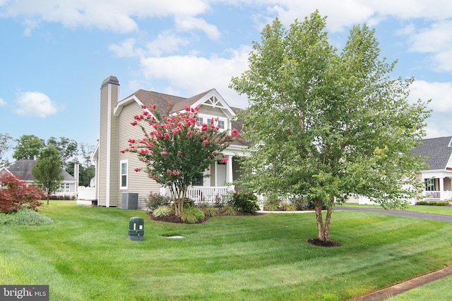 view of front of home featuring cooling unit, covered porch, and a front lawn