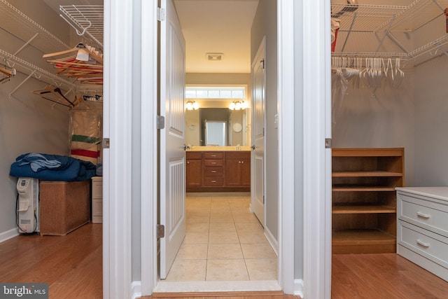 walk in closet with light hardwood / wood-style floors