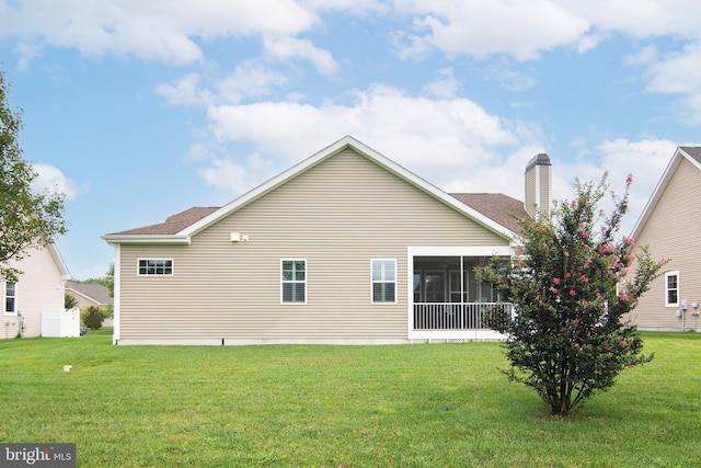 back of property with a lawn and a sunroom