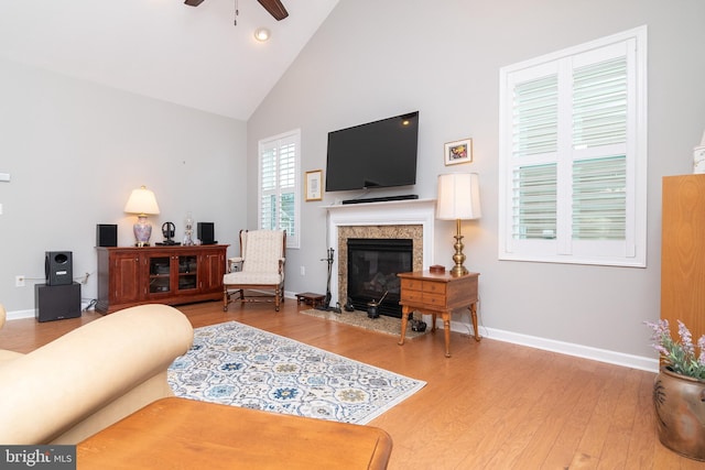 living room featuring a high end fireplace, ceiling fan, high vaulted ceiling, and hardwood / wood-style flooring