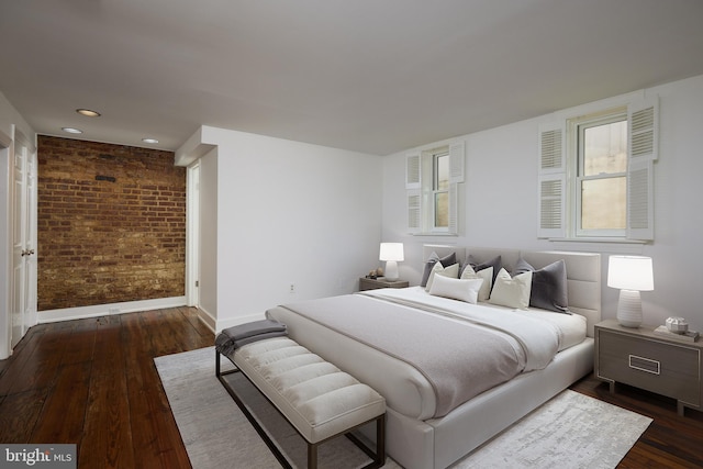 bedroom featuring brick wall and dark hardwood / wood-style flooring