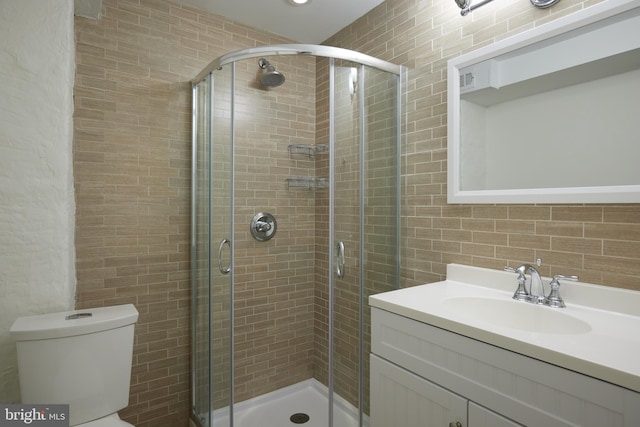 bathroom featuring a shower with door, vanity, and toilet