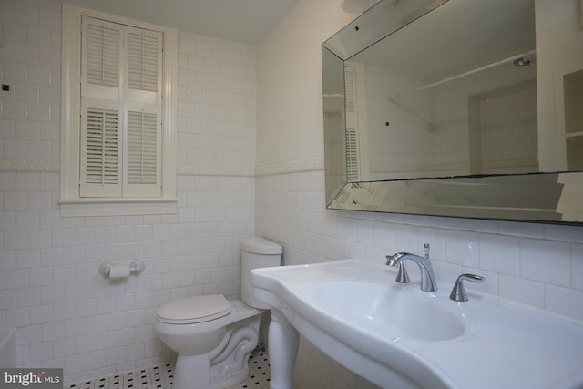 bathroom featuring tile walls, sink, toilet, and walk in shower