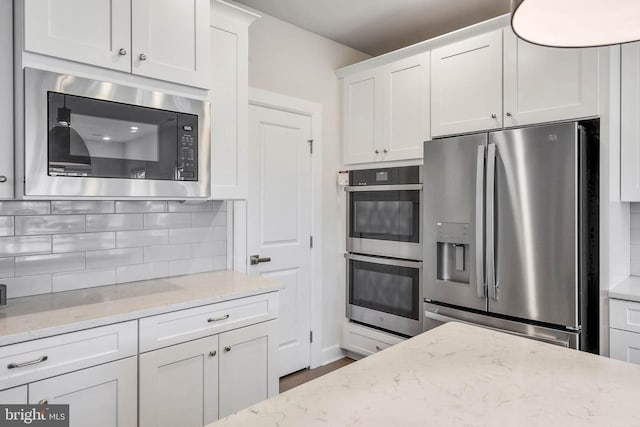 kitchen with white cabinetry, light stone countertops, decorative backsplash, and stainless steel appliances