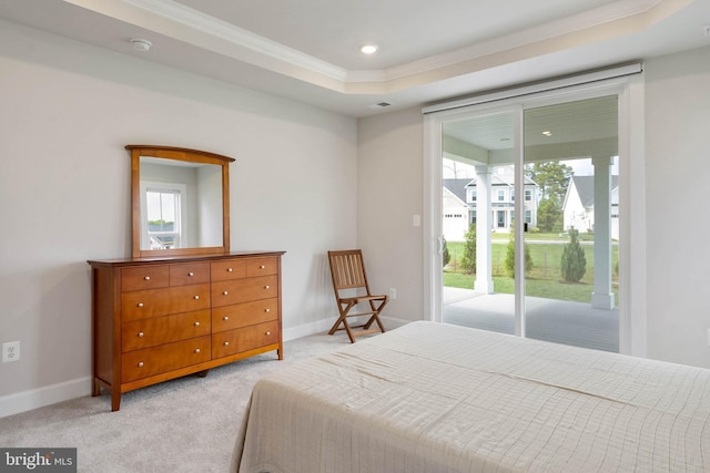 carpeted bedroom with ornamental molding, access to exterior, and a tray ceiling